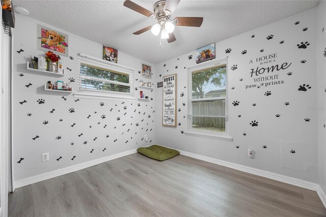 empty room with a textured ceiling, light wood-type flooring, and a healthy amount of sunlight