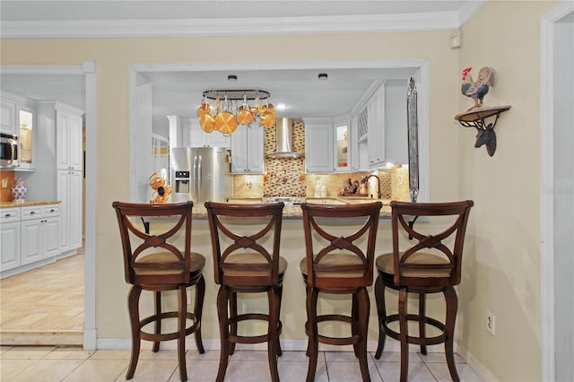 bar featuring a sink, appliances with stainless steel finishes, backsplash, wall chimney exhaust hood, and crown molding