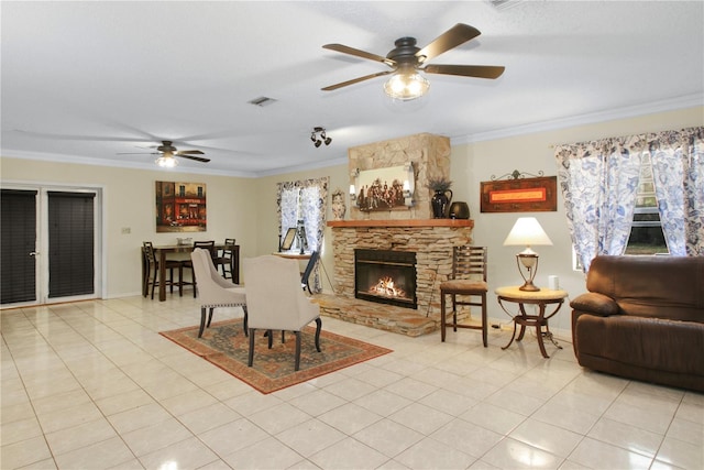 tiled living area featuring a fireplace, visible vents, baseboards, a ceiling fan, and ornamental molding