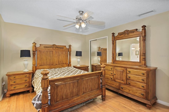 bedroom featuring light wood-style floors, a closet, visible vents, and a textured ceiling