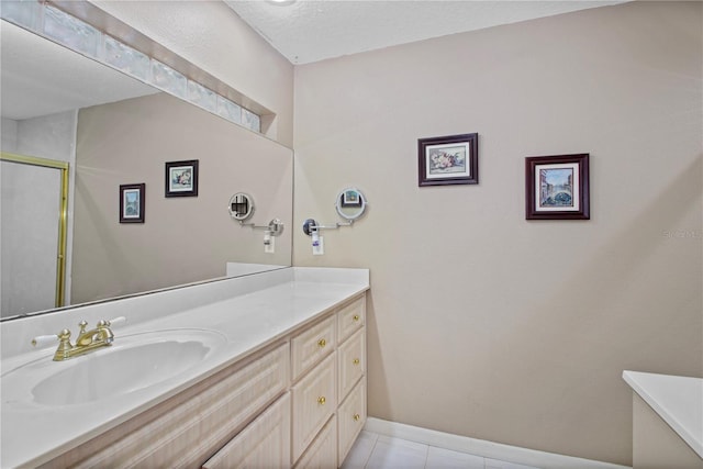 bathroom with a stall shower, tile patterned flooring, vanity, and baseboards