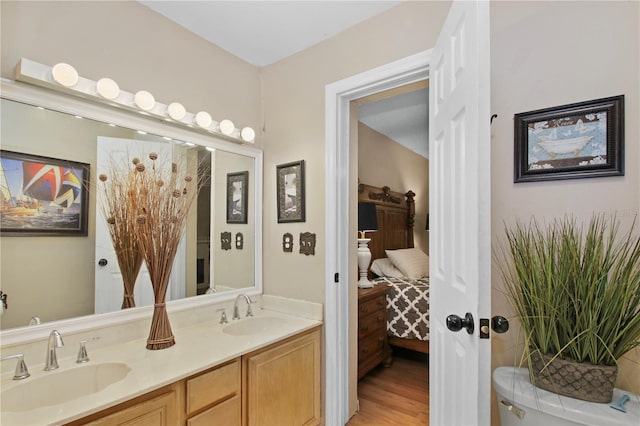 ensuite bathroom featuring ensuite bathroom, double vanity, wood finished floors, and a sink