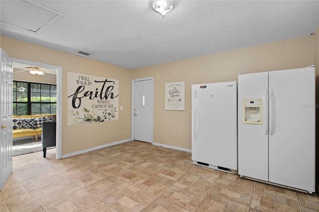 interior space with a textured ceiling, visible vents, attic access, and baseboards