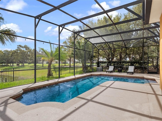 view of swimming pool featuring glass enclosure, a yard, a fenced in pool, and a patio area