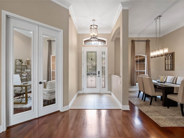 entryway with a notable chandelier, french doors, crown molding, and wood finished floors