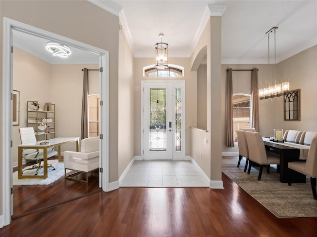 entryway with ornamental molding, baseboards, an inviting chandelier, and wood finished floors