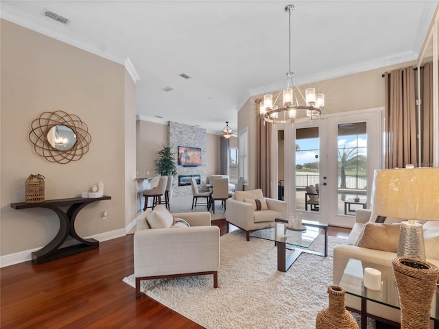 living area with crown molding, wood finished floors, baseboards, and visible vents