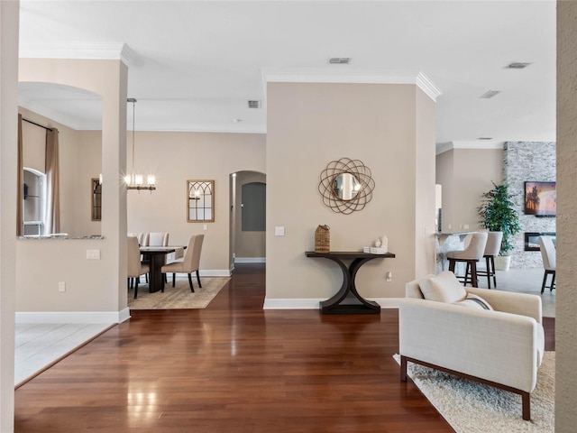 foyer entrance with visible vents, wood finished floors, arched walkways, and ornamental molding