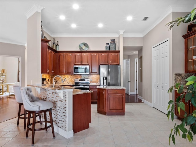 kitchen with tasteful backsplash, visible vents, a kitchen bar, appliances with stainless steel finishes, and a peninsula