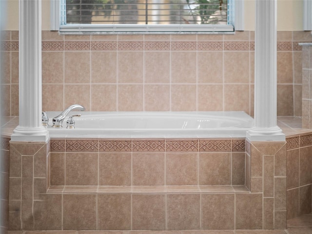 full bathroom with decorative columns and a bath