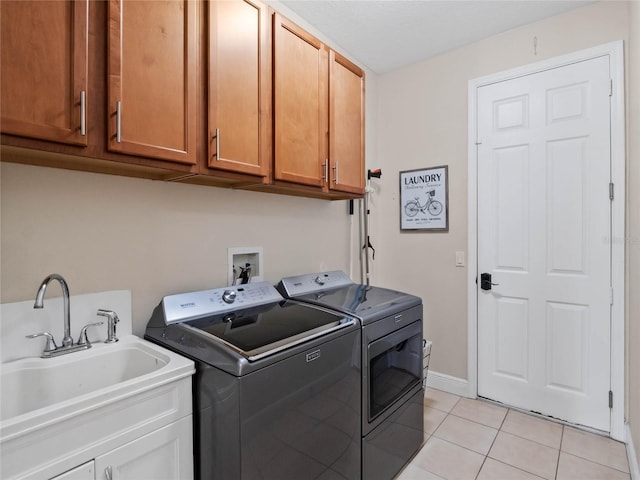 laundry area with a sink, cabinet space, light tile patterned floors, baseboards, and washing machine and clothes dryer