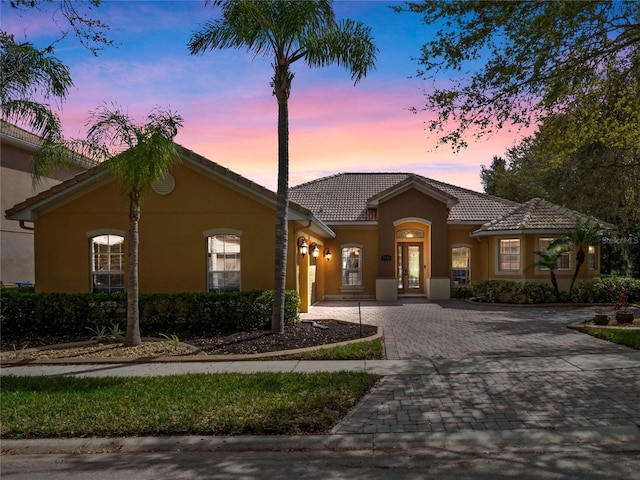 view of front facade with stucco siding, decorative driveway, and a tiled roof