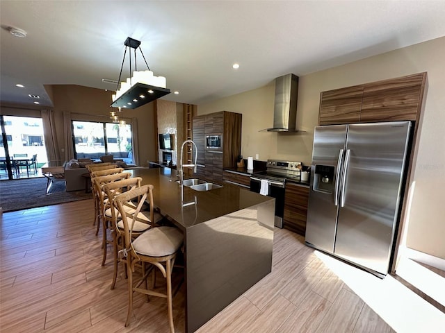 kitchen with dark countertops, wall chimney exhaust hood, modern cabinets, stainless steel appliances, and a sink