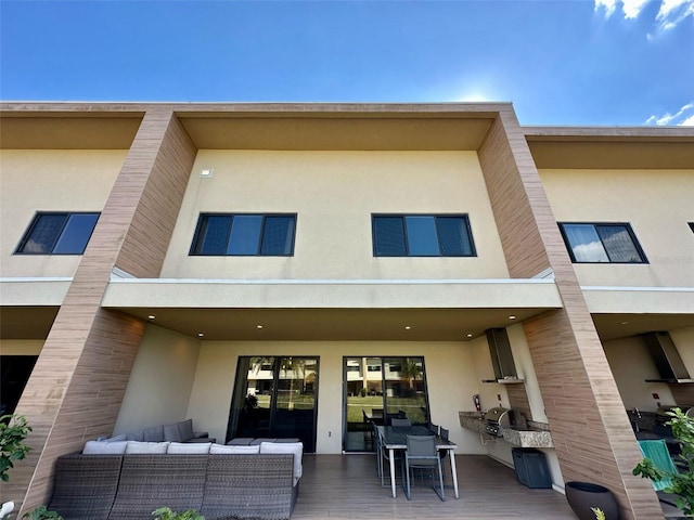 back of house with outdoor dining area, an outdoor living space, and stucco siding