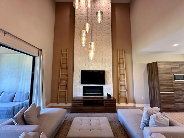 living room with a stone fireplace, a towering ceiling, and baseboards