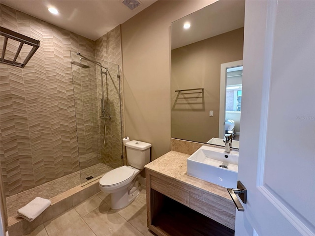 full bath featuring toilet, visible vents, vanity, tiled shower, and tile patterned floors