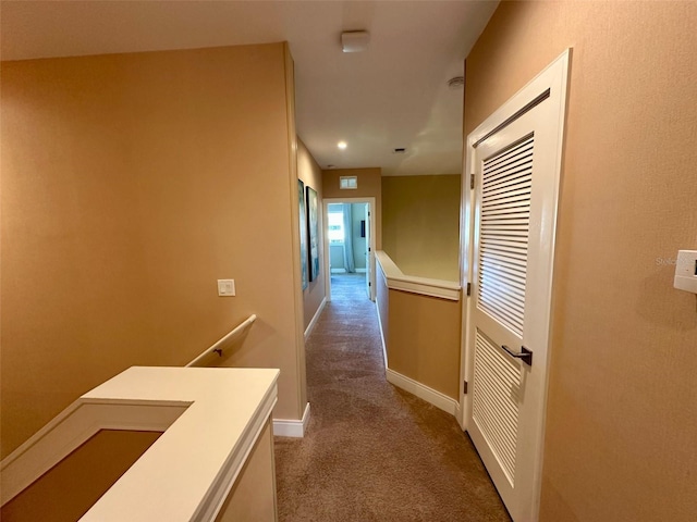 hallway featuring carpet and baseboards