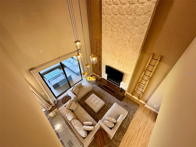 unfurnished living room featuring a fireplace, wood finished floors, a towering ceiling, and baseboards