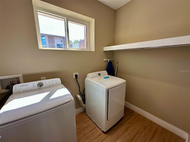 laundry area with laundry area, separate washer and dryer, light wood-type flooring, and baseboards