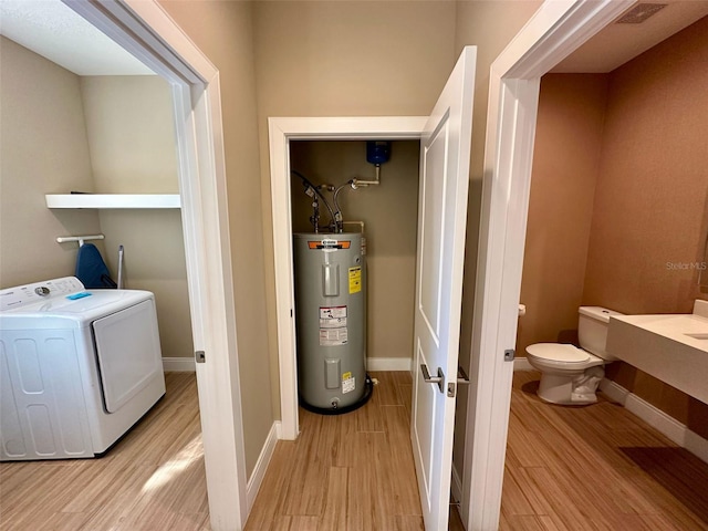 clothes washing area featuring visible vents, light wood-style floors, electric water heater, laundry area, and baseboards