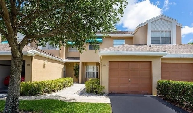 multi unit property with an attached garage, a shingled roof, aphalt driveway, and stucco siding