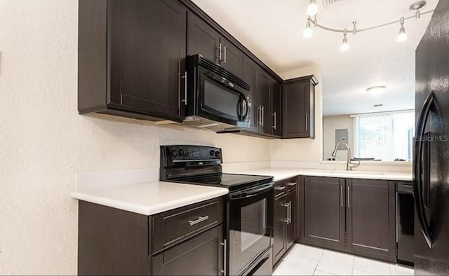 kitchen with a sink, dark brown cabinets, light countertops, black appliances, and track lighting