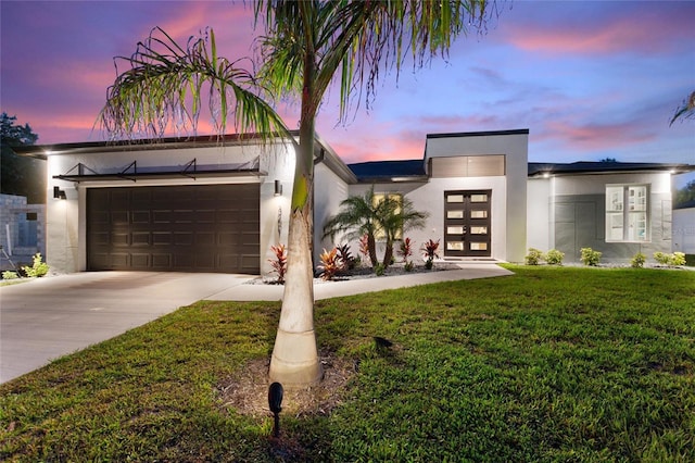 contemporary house featuring concrete driveway, french doors, a front lawn, and stucco siding