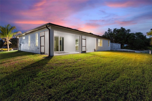 back of property featuring a yard, a patio, and stucco siding