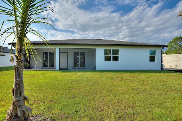 back of property featuring a sunroom, a yard, and stucco siding