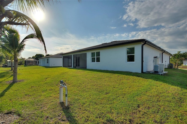 back of property with a yard and stucco siding