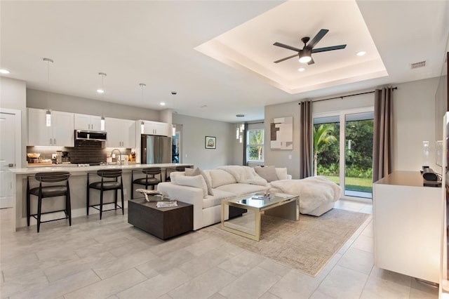 living area featuring recessed lighting, a raised ceiling, visible vents, and a ceiling fan