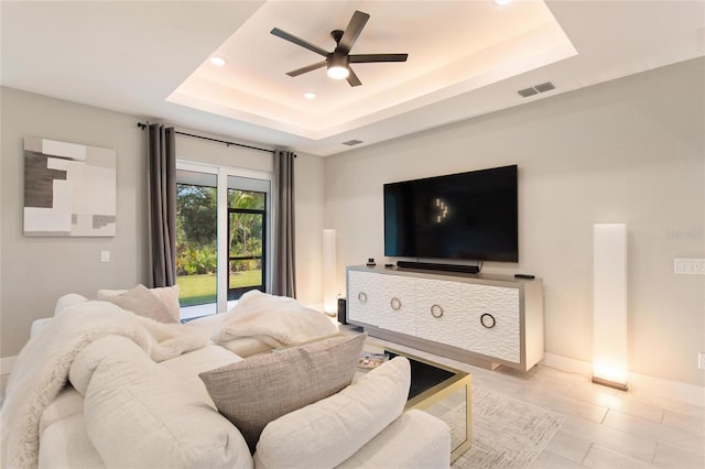 living room featuring baseboards, visible vents, a ceiling fan, a tray ceiling, and recessed lighting