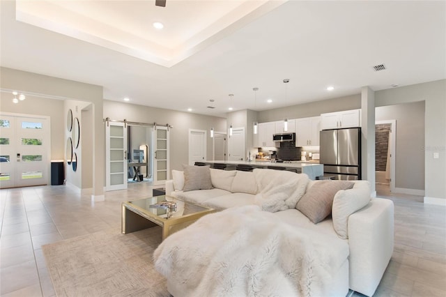 living area with recessed lighting, visible vents, baseboards, and a barn door