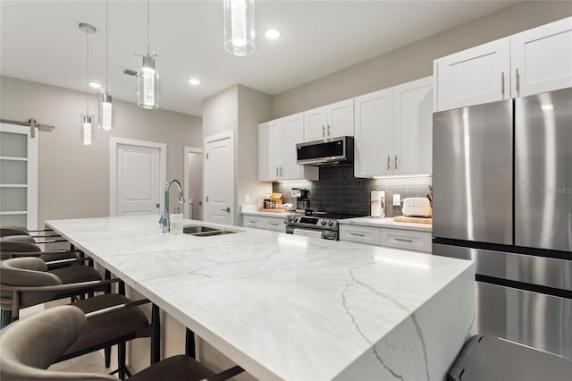 kitchen featuring a barn door, stainless steel appliances, a sink, a large island, and backsplash