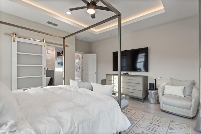 bedroom featuring a raised ceiling, visible vents, ceiling fan, and a barn door