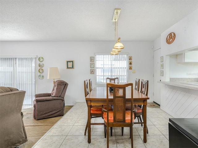 dining room featuring light tile patterned floors, plenty of natural light, and a textured ceiling