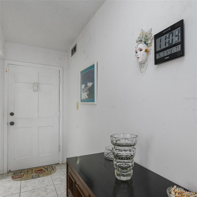 foyer entrance featuring visible vents and a textured ceiling