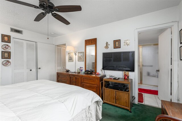 carpeted bedroom with visible vents, tile patterned floors, ensuite bathroom, a textured ceiling, and a closet