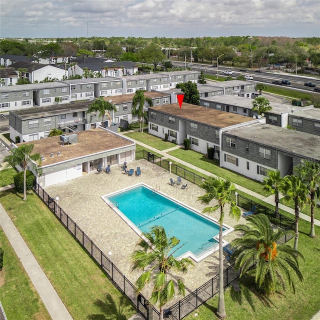 community pool with a residential view, fence, and a lawn