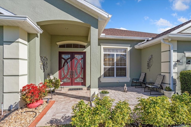 property entrance with stucco siding and roof with shingles