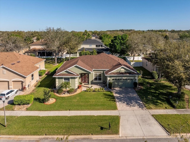 view of front of home with a garage, concrete driveway, a front lawn, and a residential view