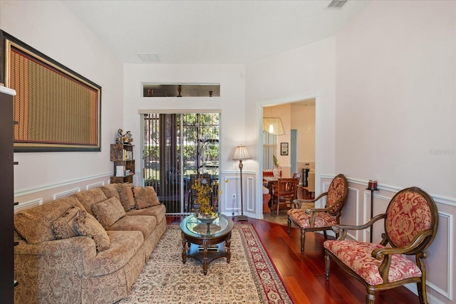 living area featuring a wainscoted wall, wood finished floors, and a decorative wall