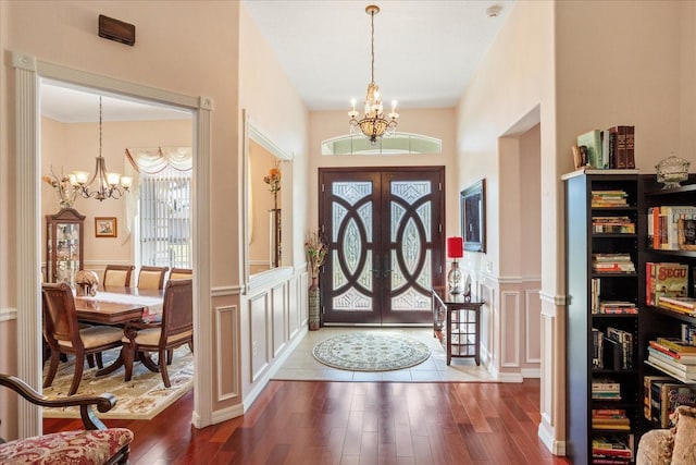 entryway featuring a decorative wall, a wainscoted wall, an inviting chandelier, and wood finished floors