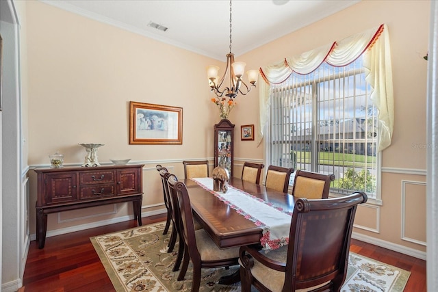 dining room with visible vents, ornamental molding, dark wood-style floors, an inviting chandelier, and wainscoting