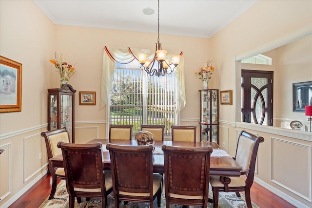 dining space with dark wood-type flooring, a healthy amount of sunlight, wainscoting, and a chandelier