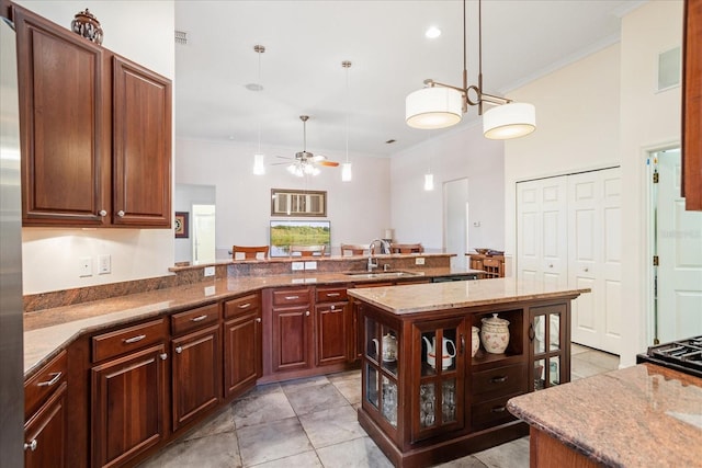 kitchen featuring pendant lighting, ornamental molding, a ceiling fan, a sink, and a peninsula