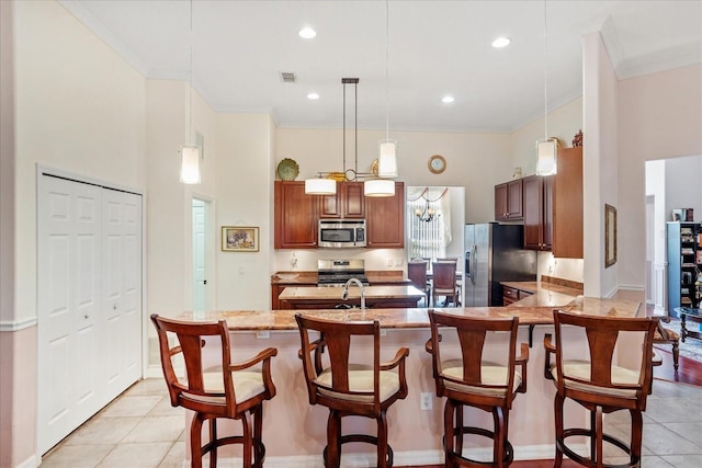 kitchen with a breakfast bar area, visible vents, a peninsula, ornamental molding, and stainless steel appliances