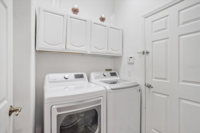 clothes washing area featuring cabinet space and independent washer and dryer