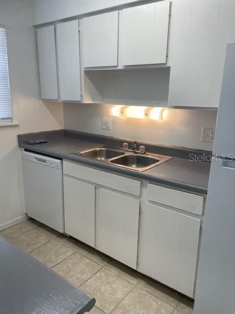 kitchen featuring white cabinetry, white appliances, dark countertops, and a sink