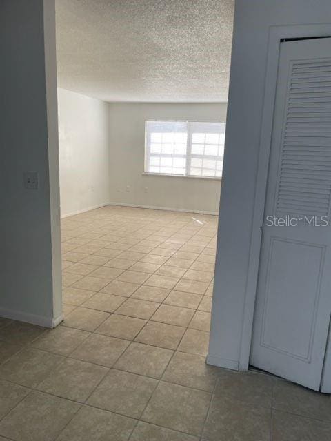 tiled spare room featuring baseboards and a textured ceiling